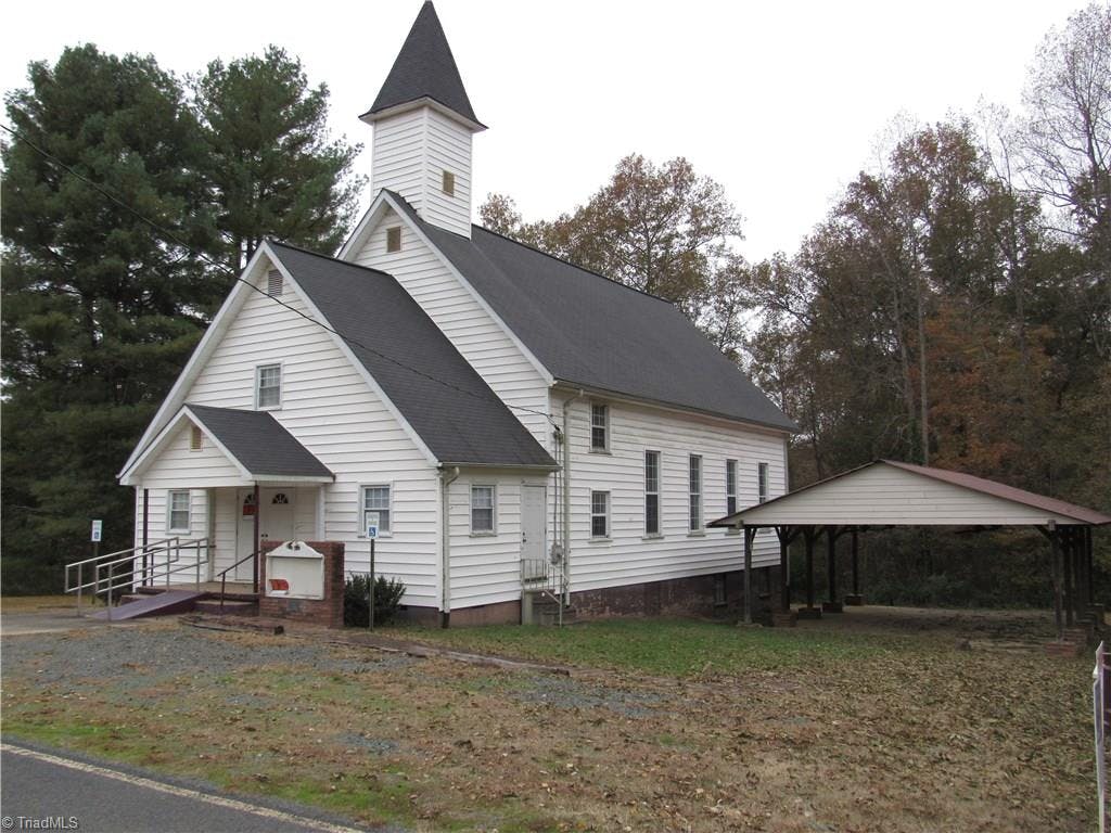 View of front right of church showing stoop, ramp, steeple, sign, and large covered entertainment area.  36 X 27 foot Covered shed has several electrical outlets, fans, and lighting.