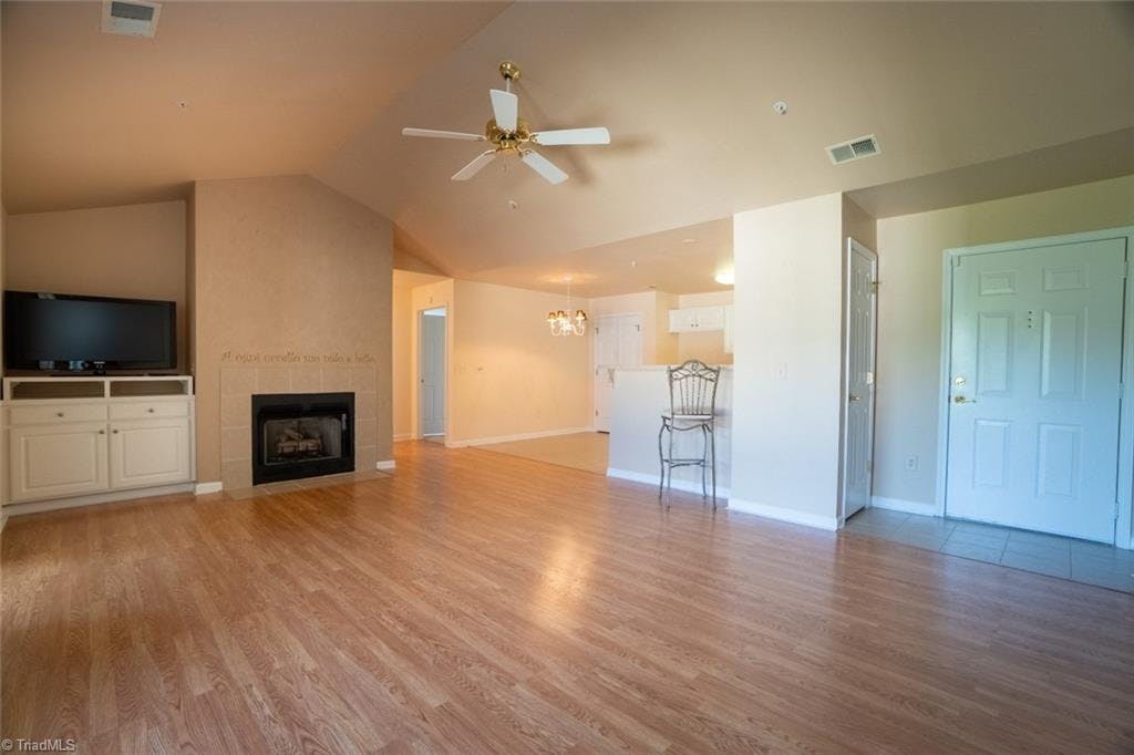 The smooth, vaulted ceiling and beautiful floors make this living room spacious and inviting.  Front door is to the right, with the breakfast area visible in the background. There are gas logs in the fireplace.