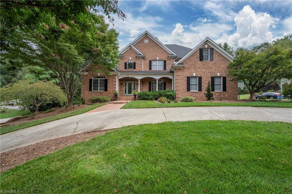 Stunning front elevation with brick quoins, bullnosed steps to covered front porch, circular driveway, basement driveway.